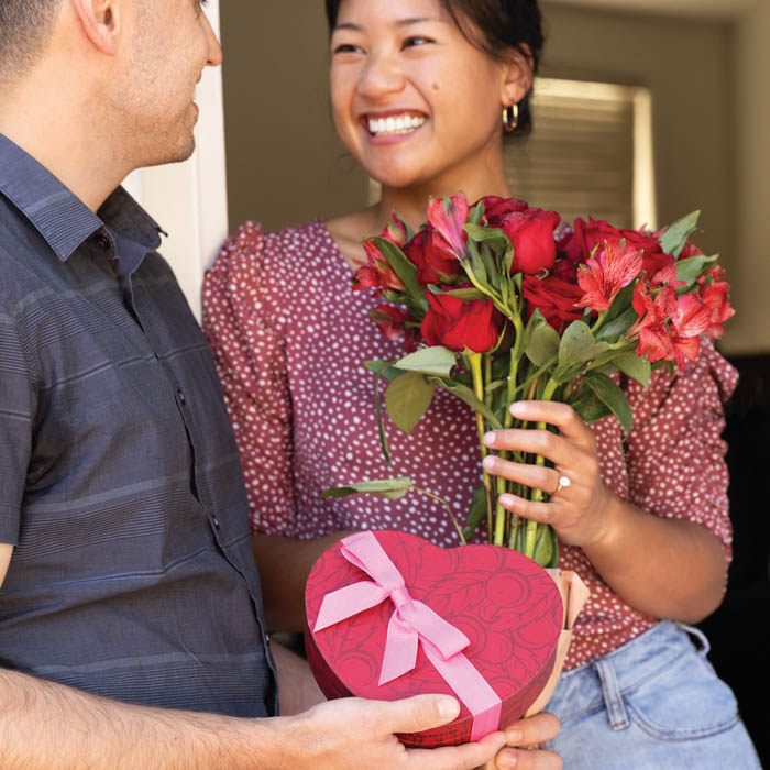 Man giving Cherry Valentine Heart Box and flowers to smiling woman