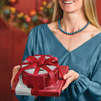 Closed assortment and tin tied with a red bow being hand delivered