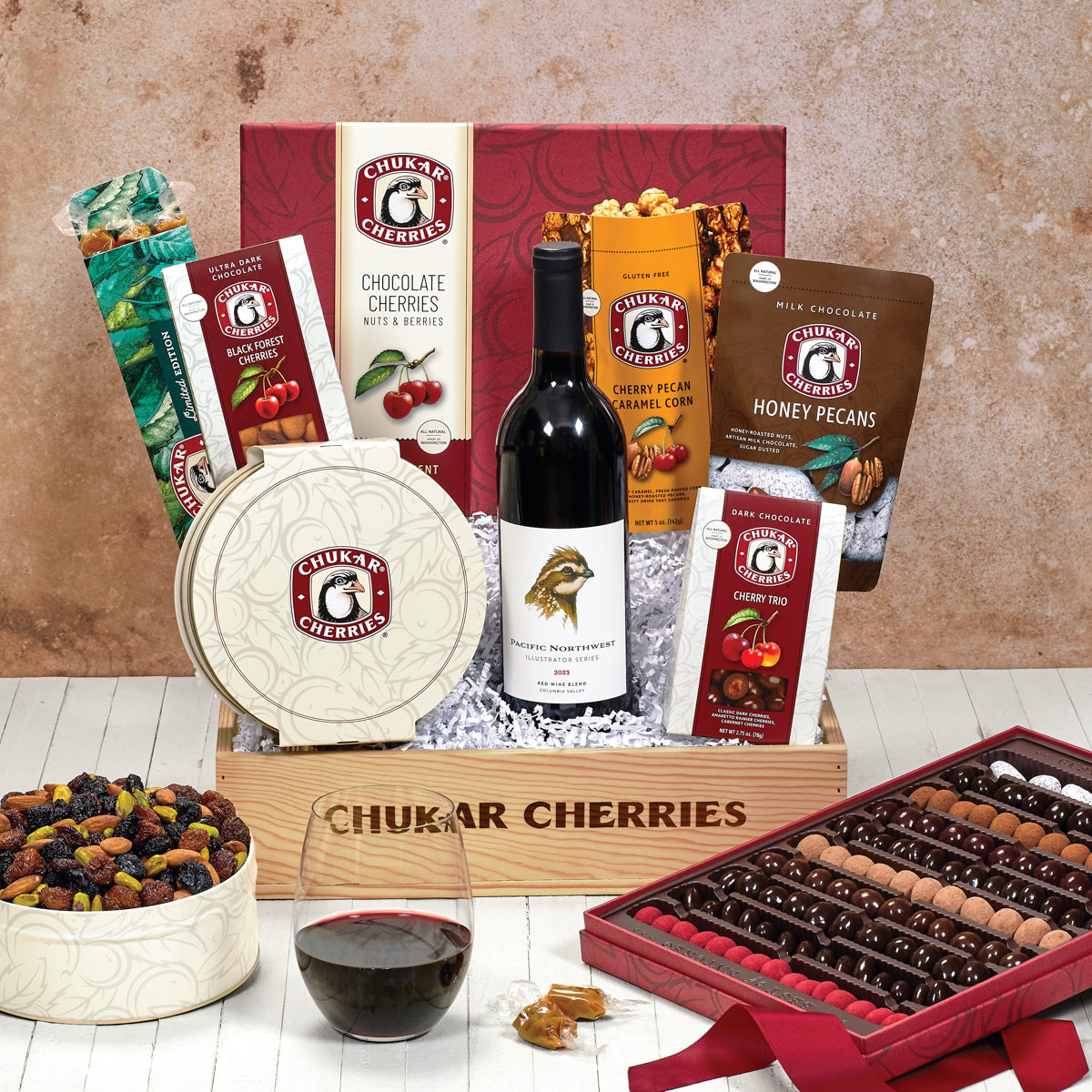 Gift pictured with columbia valley red blend, grand assortment, triple cherry nut tin, milk chocolate honey pecans, cherry caramel twists, cherry pecan caramel corn, black forest cherries, and cherry trio 