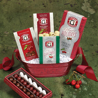 Closed boxes of classic milk chocolate and ultra dark chocolate black forest cherries, and open cherry christmas white chocolate tart cherries and happy holidays classic assortment included in holiday cherry and nut gift basket