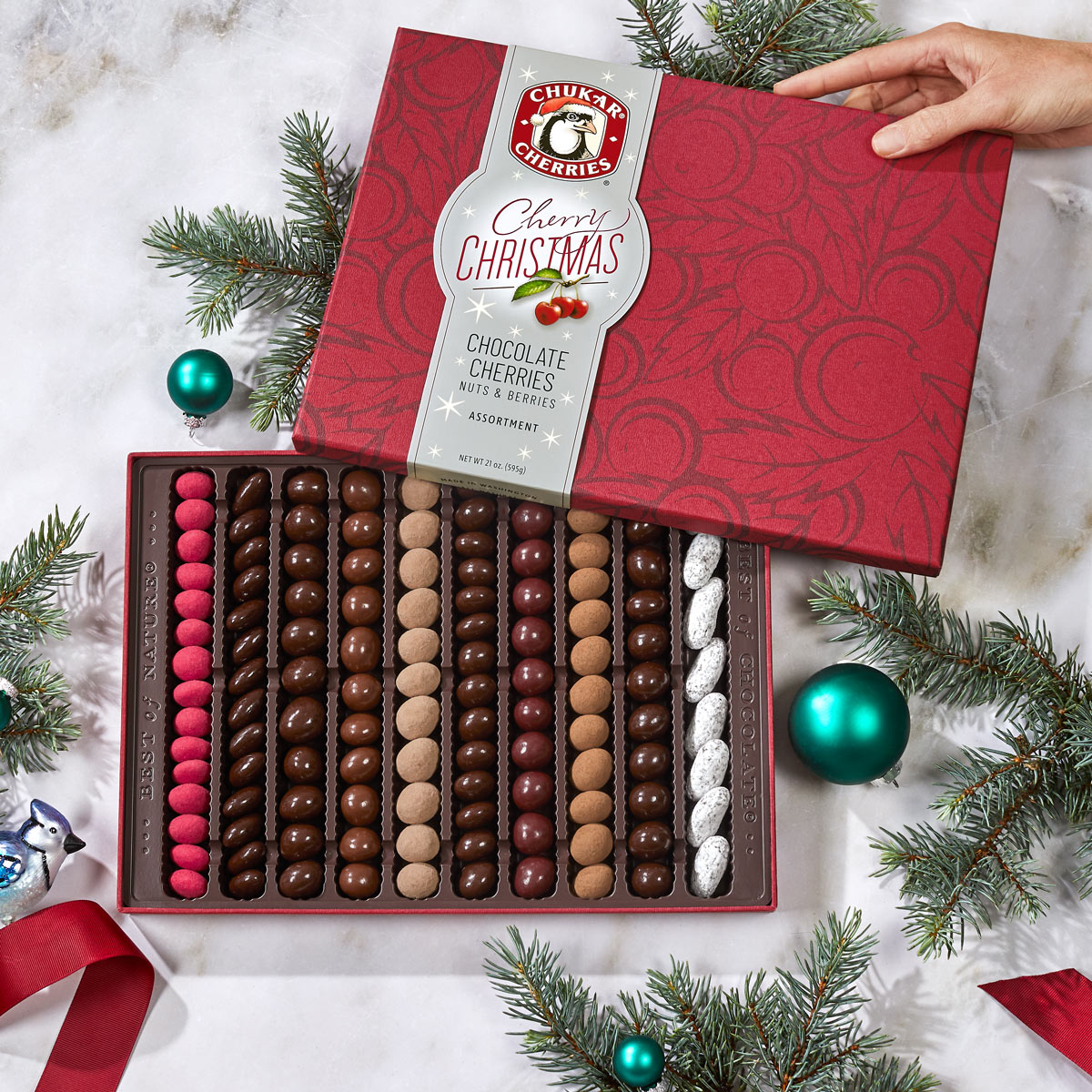 Open cherry christmas grand chocolate assortment gift box showing ten rows filled with chocolate covered cherries, nuts, and berries.