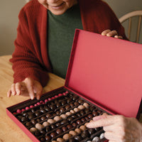 Two people picking a chocolate from a grand assortment
