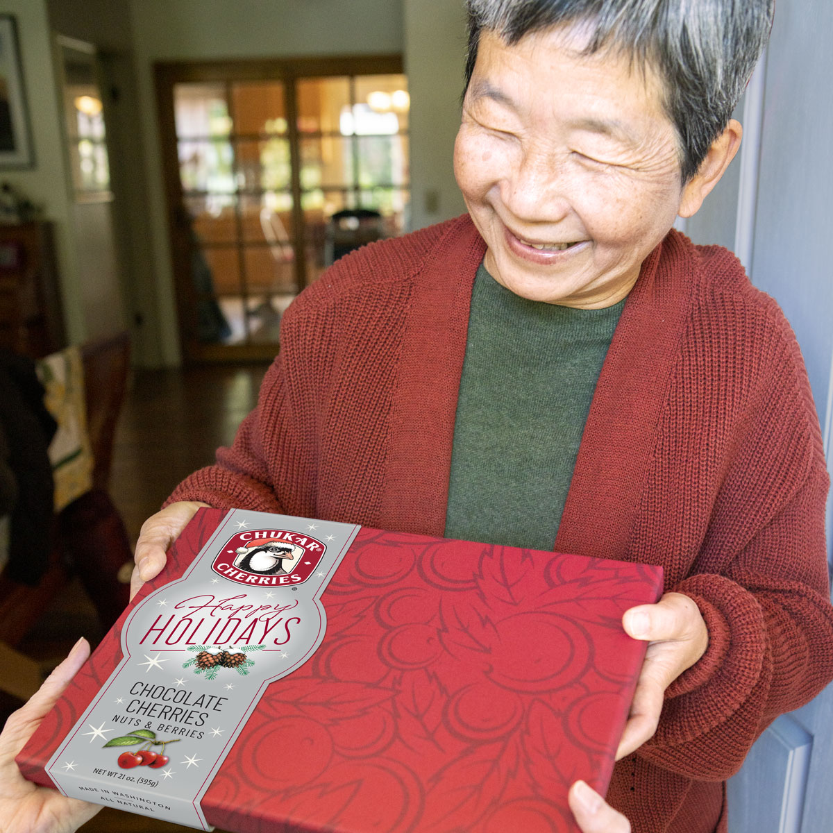 Women smiling as she holding a happy holidays grand assortment