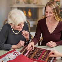 Two smiling women picking chocolate covered cherries out of happy holidays sumptuous assortment 