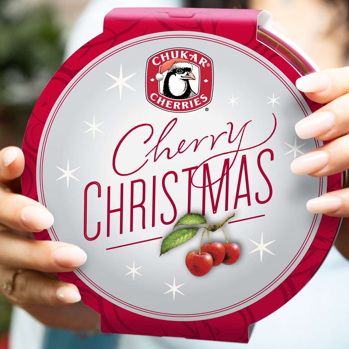 Cherry christmas tin being held with close up view of top