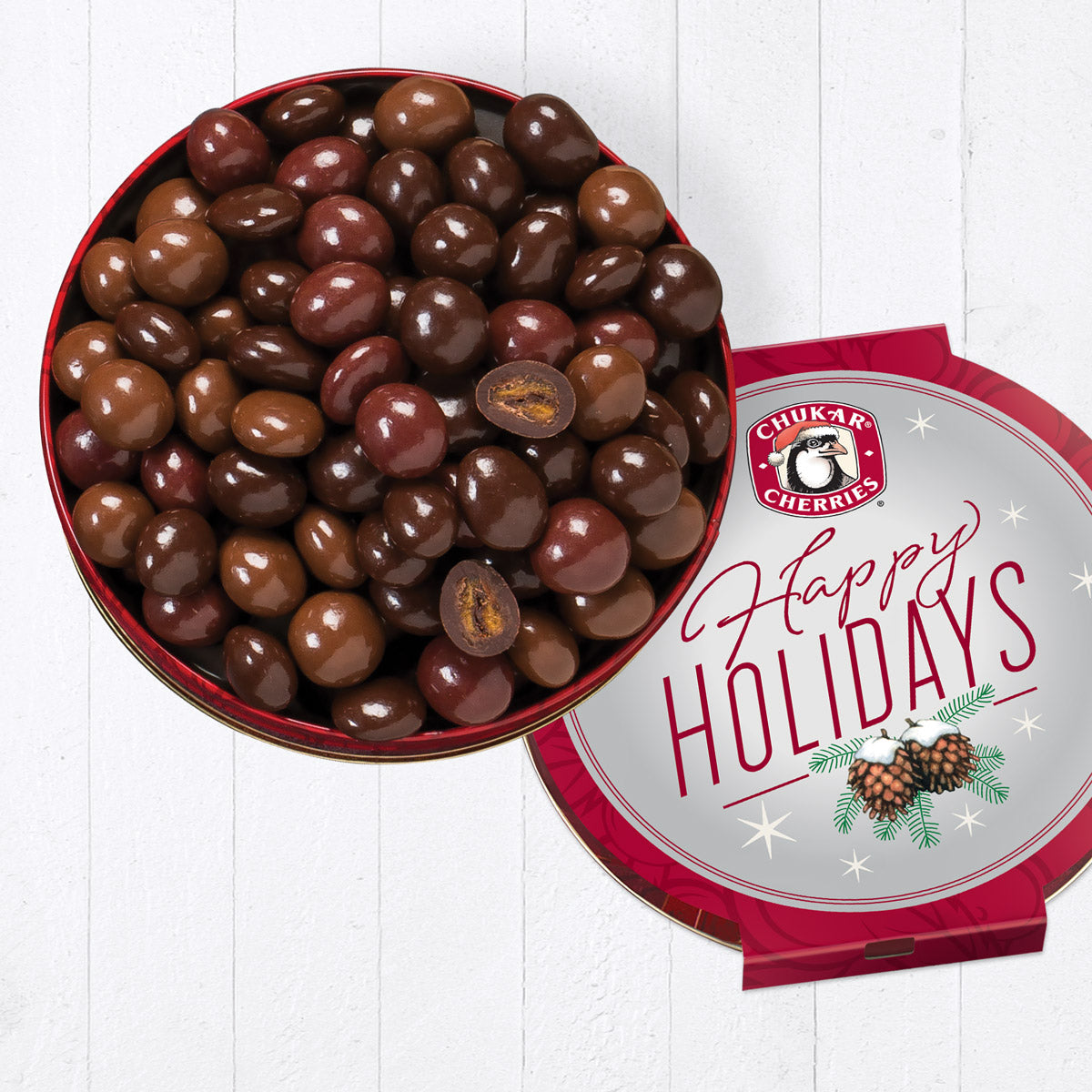 Open happy holidays cherry quartet tin showing whole dark chocolate cabernet cherries, milk chocolate cherry bings, classic milk chocolate cherries, and whole and cut ultra dark chocolate amaretto rainiers.
