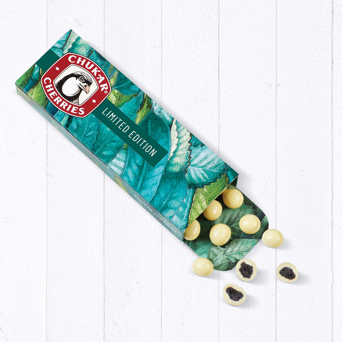 Spill of white chocolate blueberries in open limited edition box with cut of chocolates
