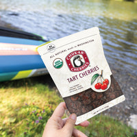 Hand holding organic tart cherries bag with river in the background