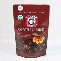 Whole and cut ultra dark chocolate organic chipotle cherries shown in closed resealable bag