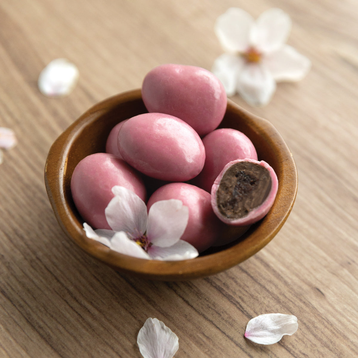 Whole and cut white and dark chocolate cherry blossoms shown in bowl with cherry blossom bloom