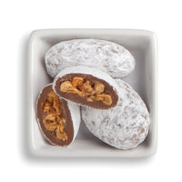 Whole and cut honey pecans in white bowl
