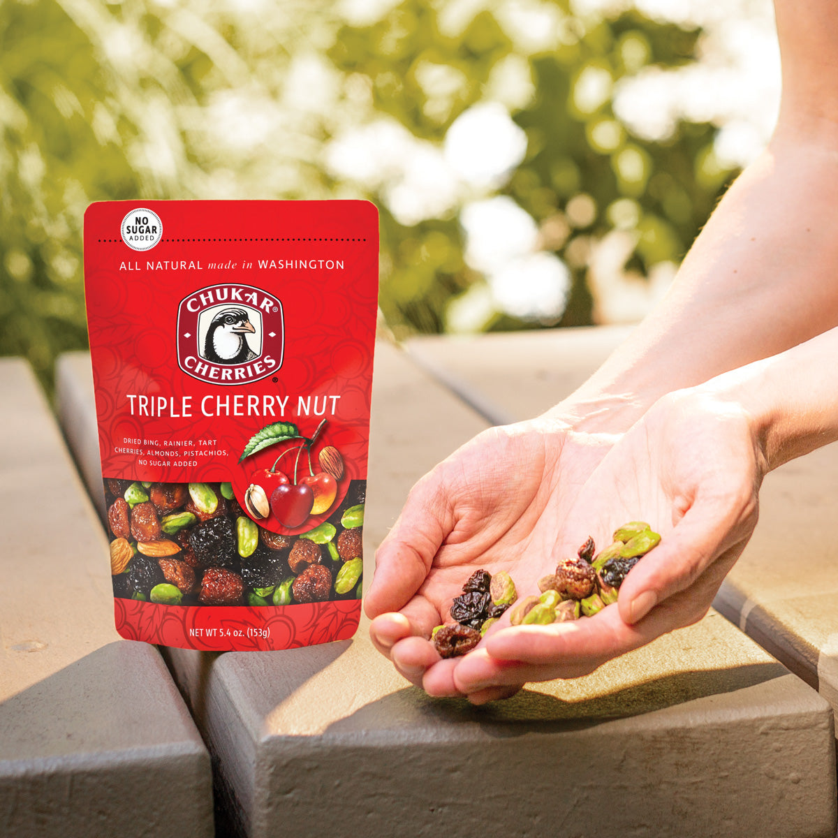 Woman holding handful of triple cherry nut next to bag