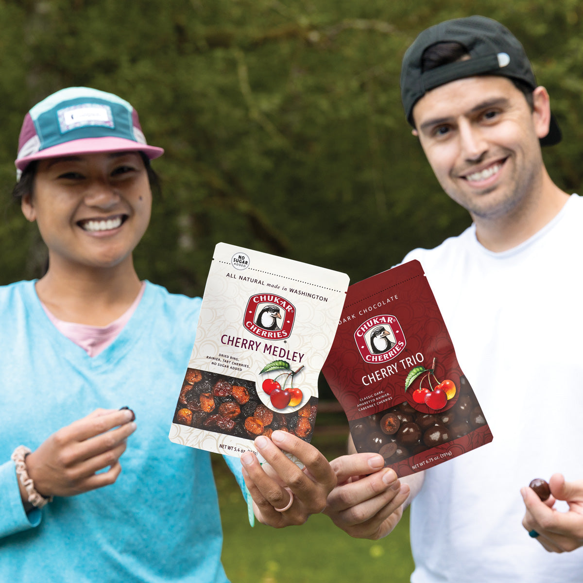 Woman and man holding bags of cherry medley and cherry trio in outdoor setting