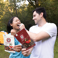 Two people outdoors having fun feeding each other cherry trio and cherry medley cherries.