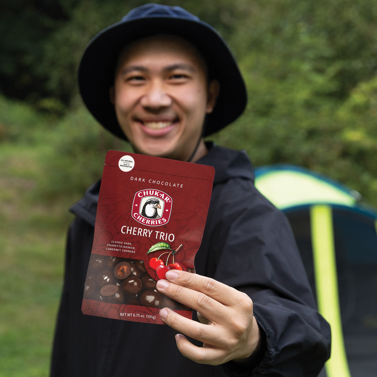 Man at campsite holding bag of cherry trio