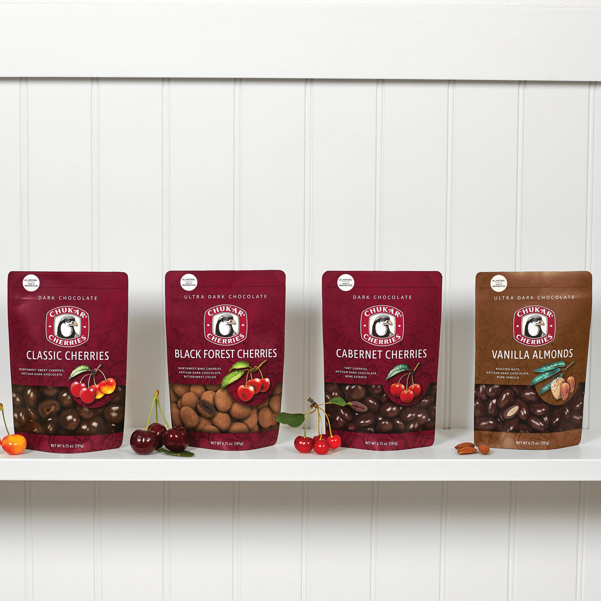 Cut and whole classic dark chocolate cherries, ultra dark chocolate black forest cherries, dark chocolate cabernet cherries, and ultra dark chocolate vanilla almonds shown on bags in dark chocolate bundle