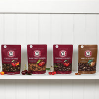 Cut and whole classic dark chocolate cherries, ultra dark chocolate black forest cherries, dark chocolate cabernet cherries, and ultra dark chocolate vanilla almonds shown on bags in dark chocolate bundle